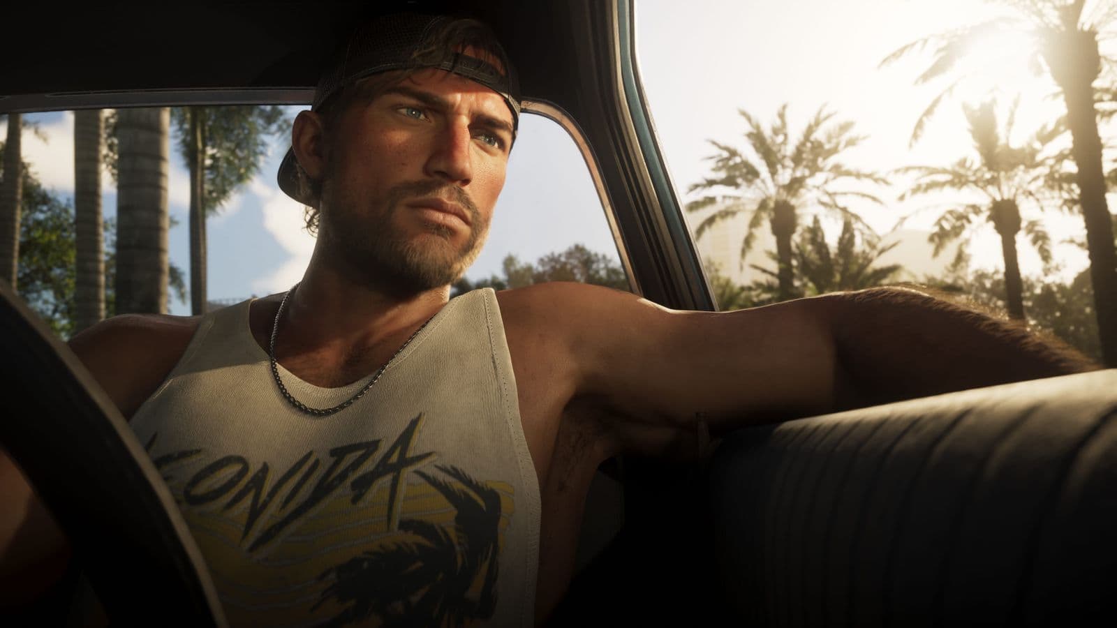 Jason Duval in a Leonida tank top and backwards cap, sitting in a car with palm trees behind him
